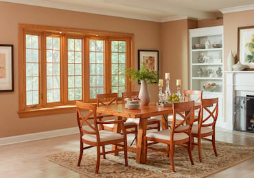 A dining room featuring a wooden table surrounded by four chairs, with soft lighting creating a warm atmosphere.