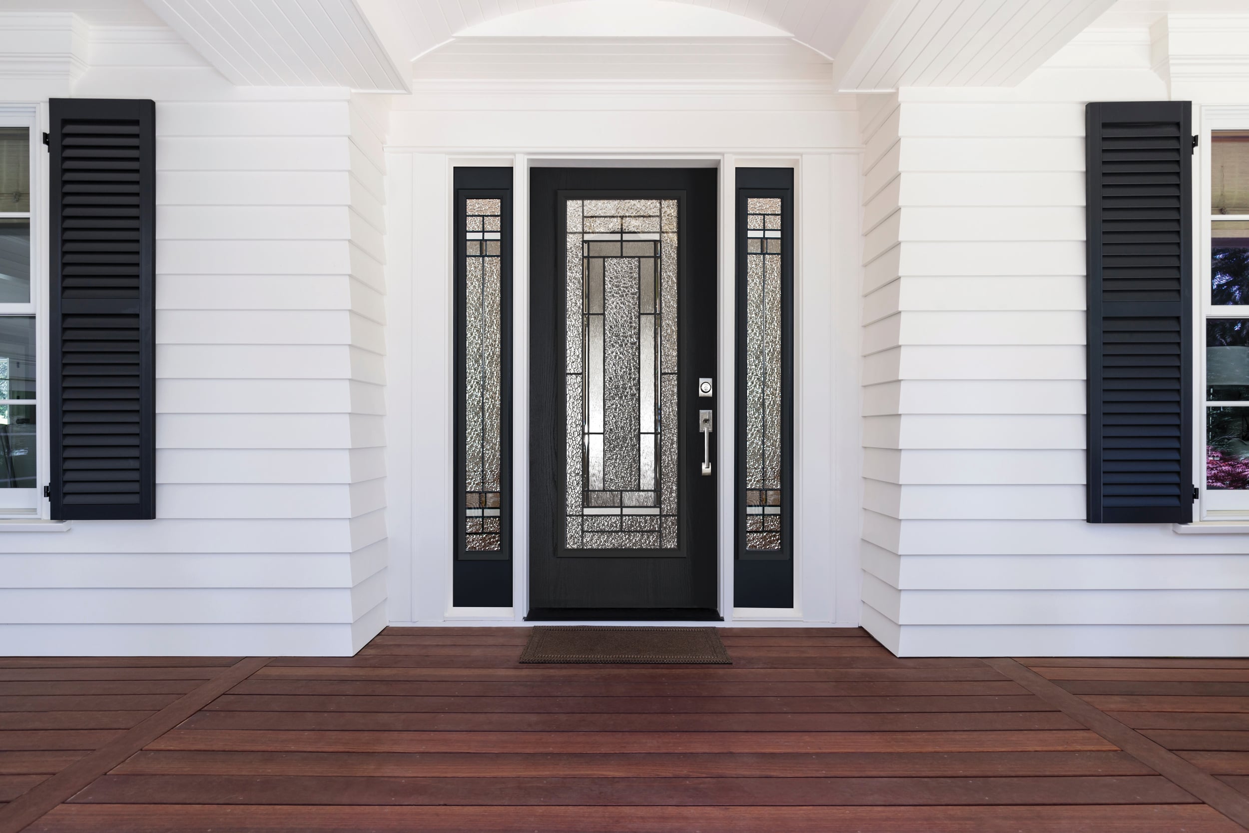 A black door with white shutters on a residential home, showcasing a classic and elegant exterior design.