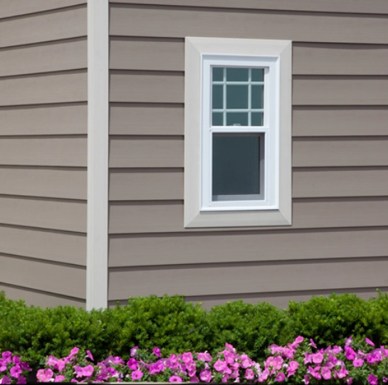 A house with a window, complemented by a garden of flowers in front.